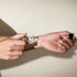 Person applying perfume to their wrist with a small bottle.