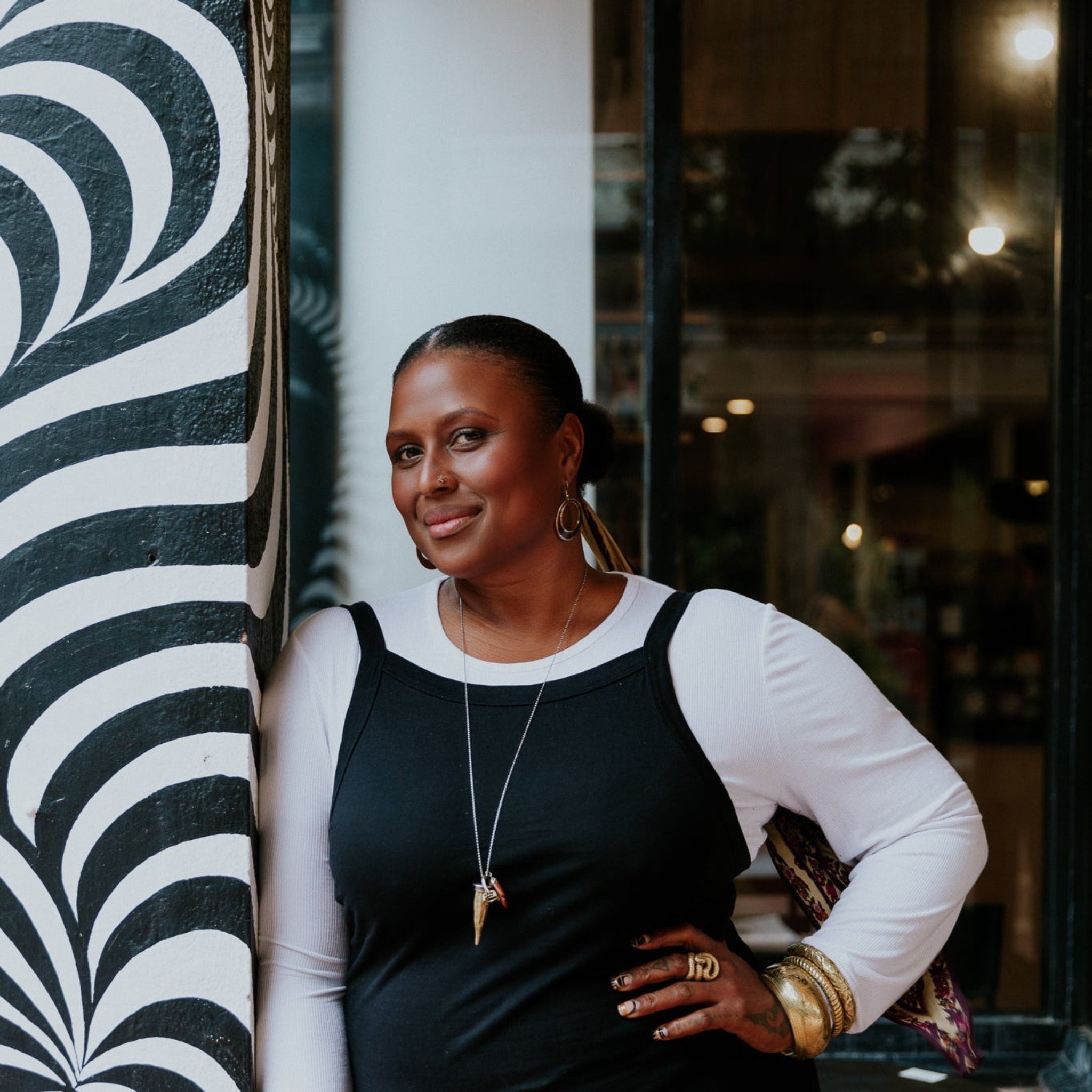 Woman standing in front of a store with a decorative wall.