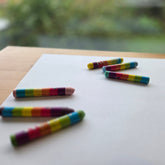 Colorful crayon pieces on a white sheet of paper with a blurred natural background
