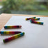 Colorful crayon pieces on a white sheet of paper with a blurred natural background