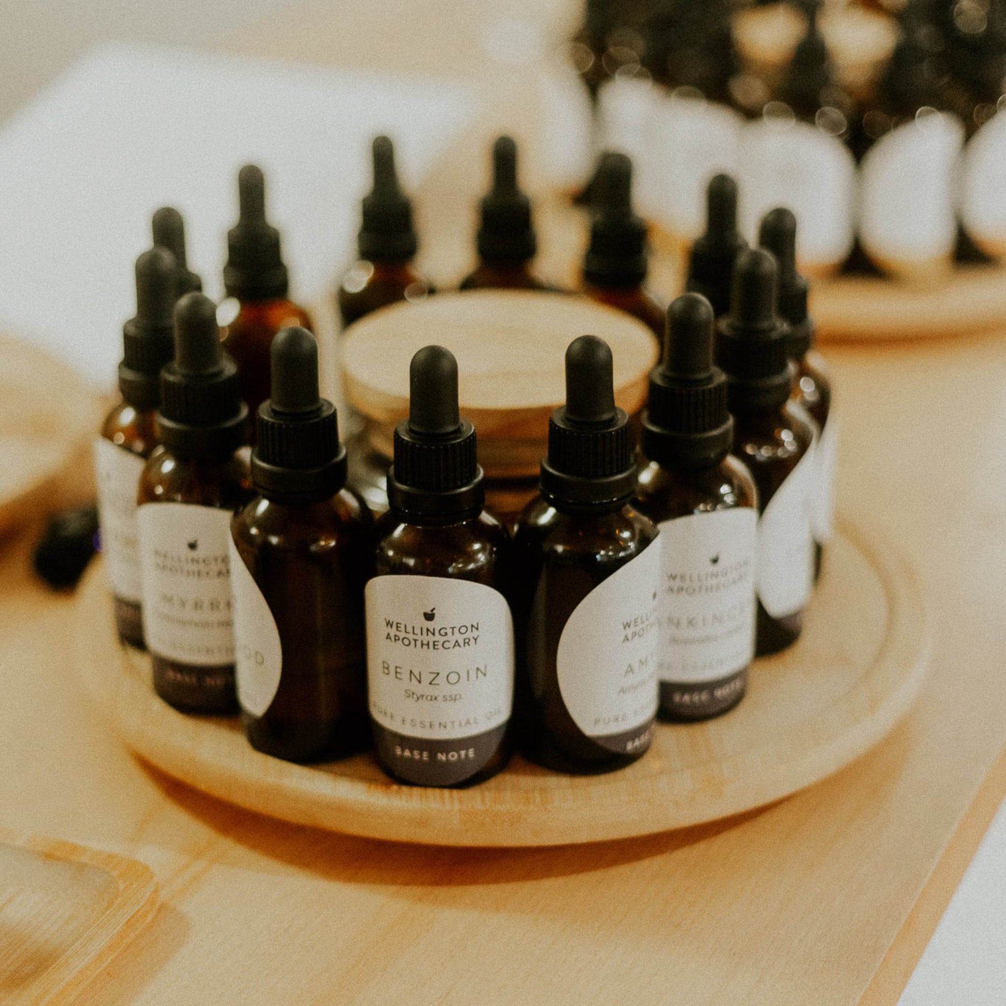 Collection of dark glass bottles with dropper caps on a wooden tray.
