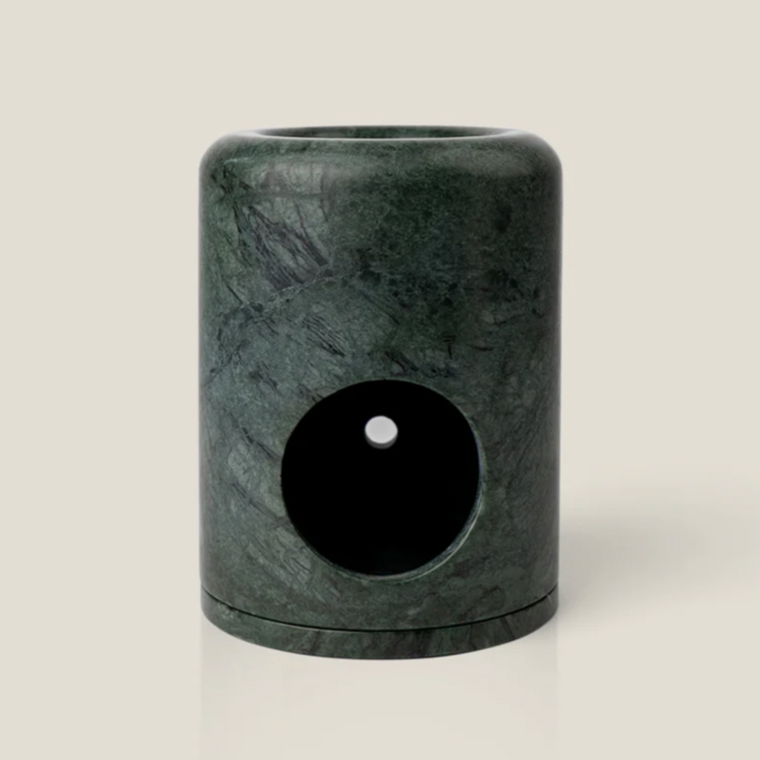 Dark green marble oil burner on white surface and white background. 