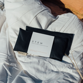 Two midnight coloured linen eye pillows on a duvet in the sunshine. 