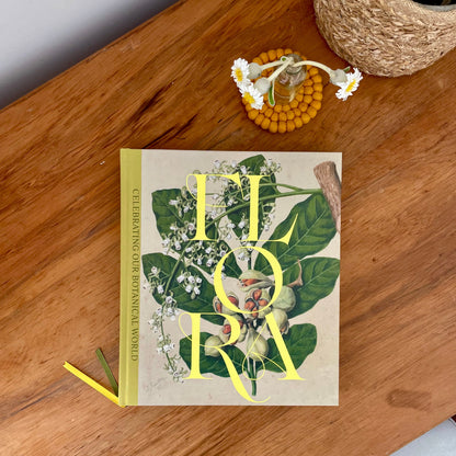 A book called FLORA on a wooden desk with daisies