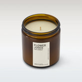 Flower junkie candle in amber glass jar with lid off on white background. 