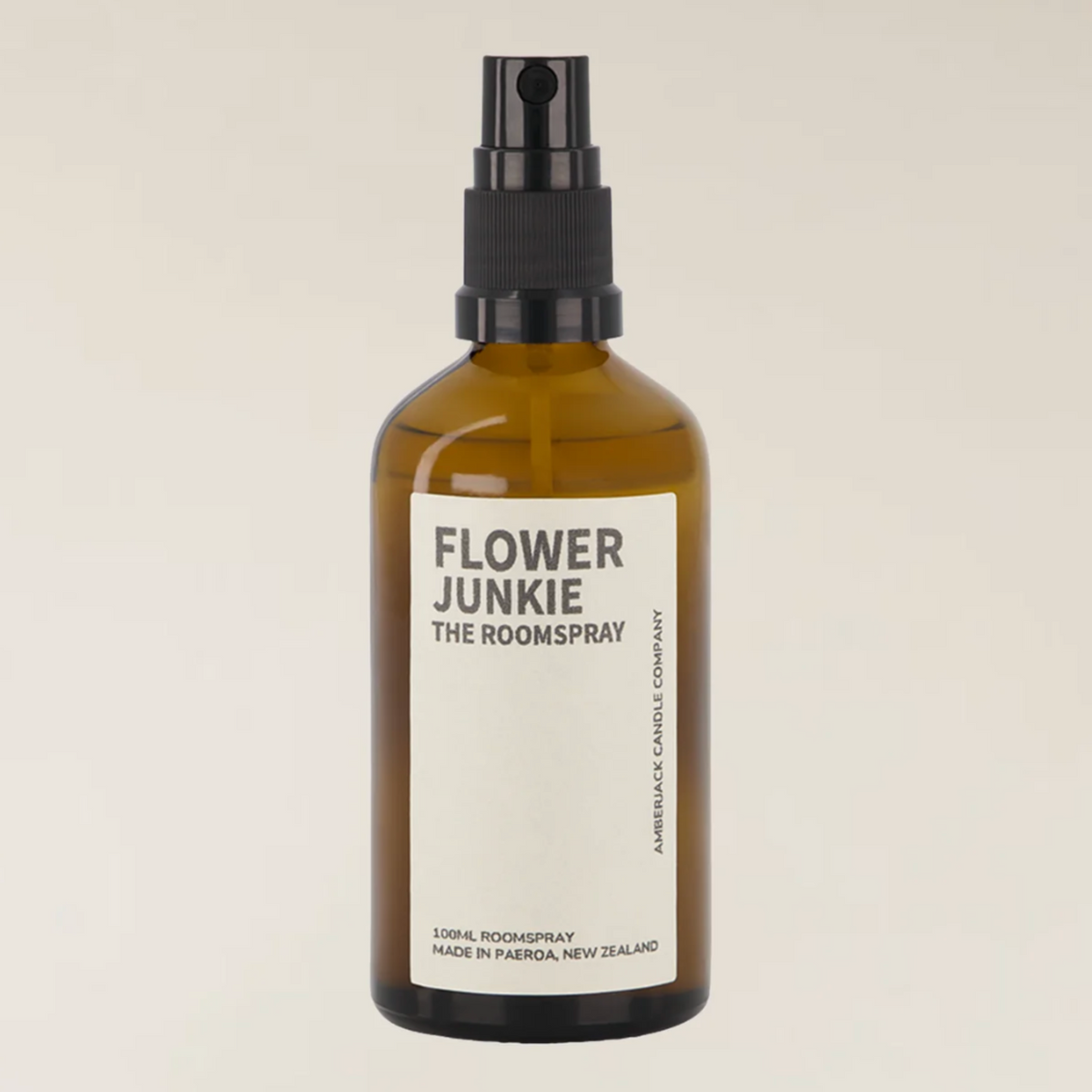 An amber glass room spray bottle with a black spray nozzle and a white label reading &