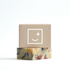 Bar of soap with a colorful design on a beige box featuring a smiley face symbol.