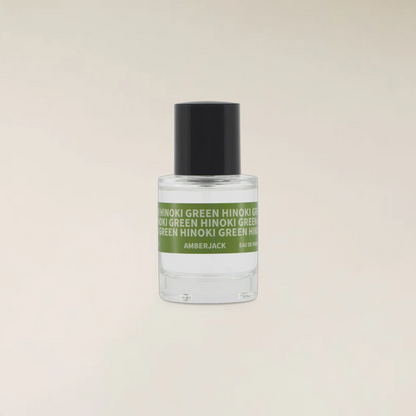 A small clear glass bottle of Amberjack fragrance with a black cap and a green label reading &