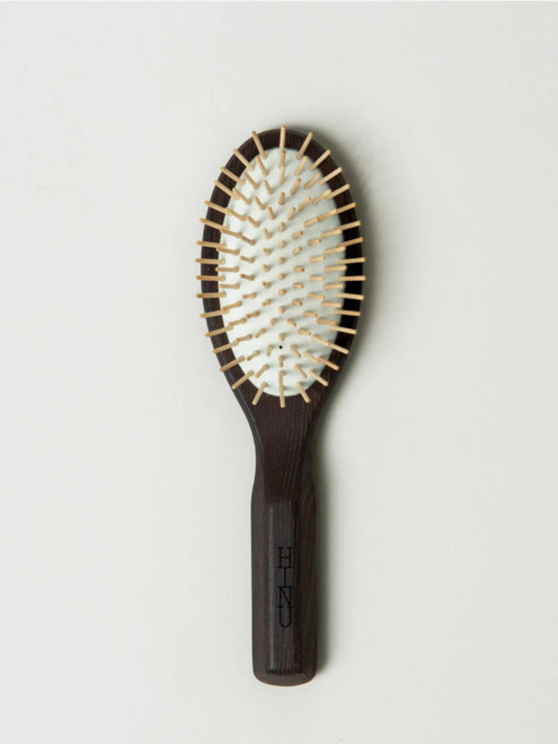 Hairbrush with wooden handle and metal bristles on a light gray background