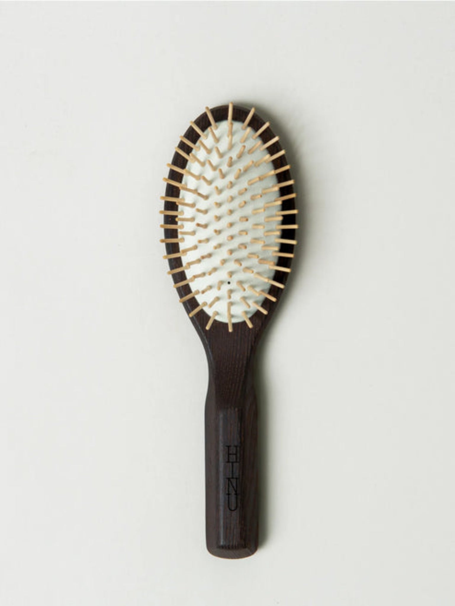 Hairbrush with wooden handle and metal bristles on a light gray background