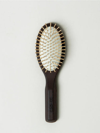 Hairbrush with wooden handle and metal bristles on a light gray background