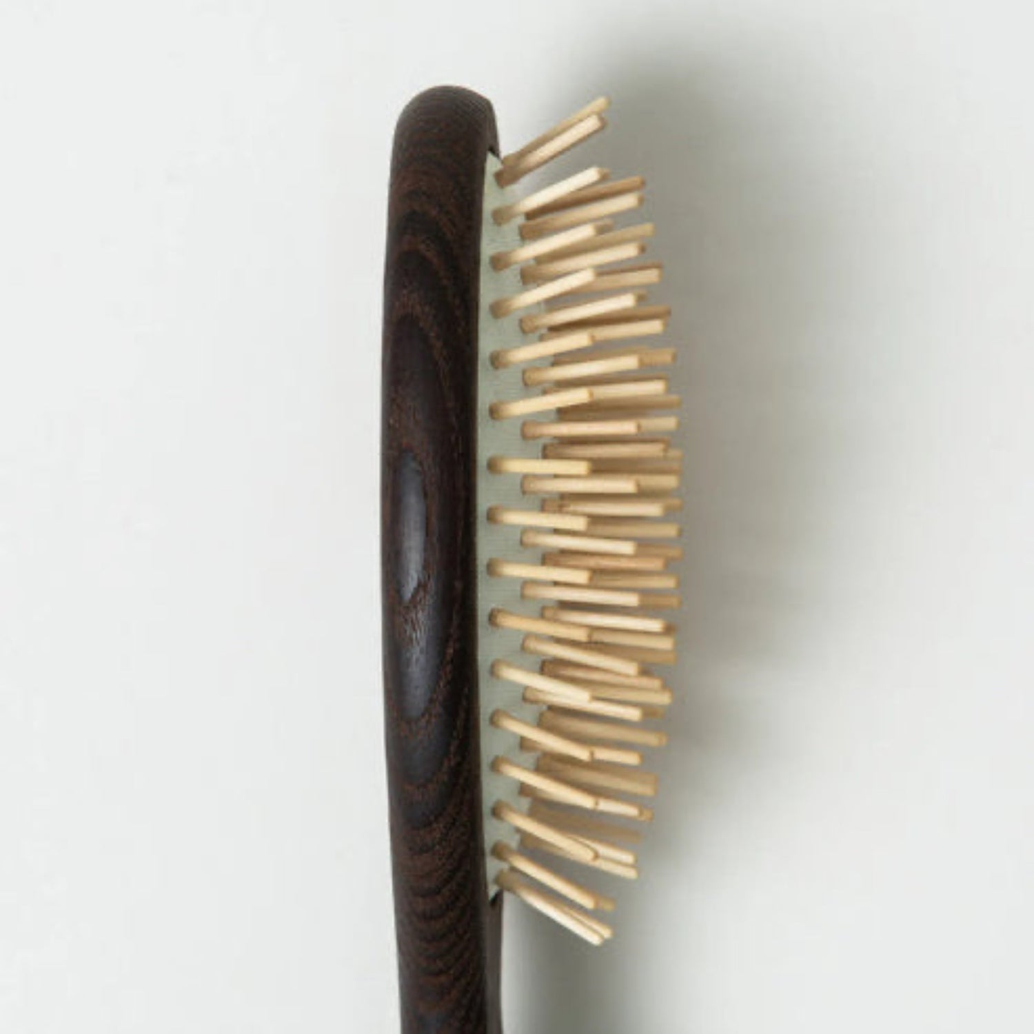 Wooden hairbrush with a dark handle on a light gray background
