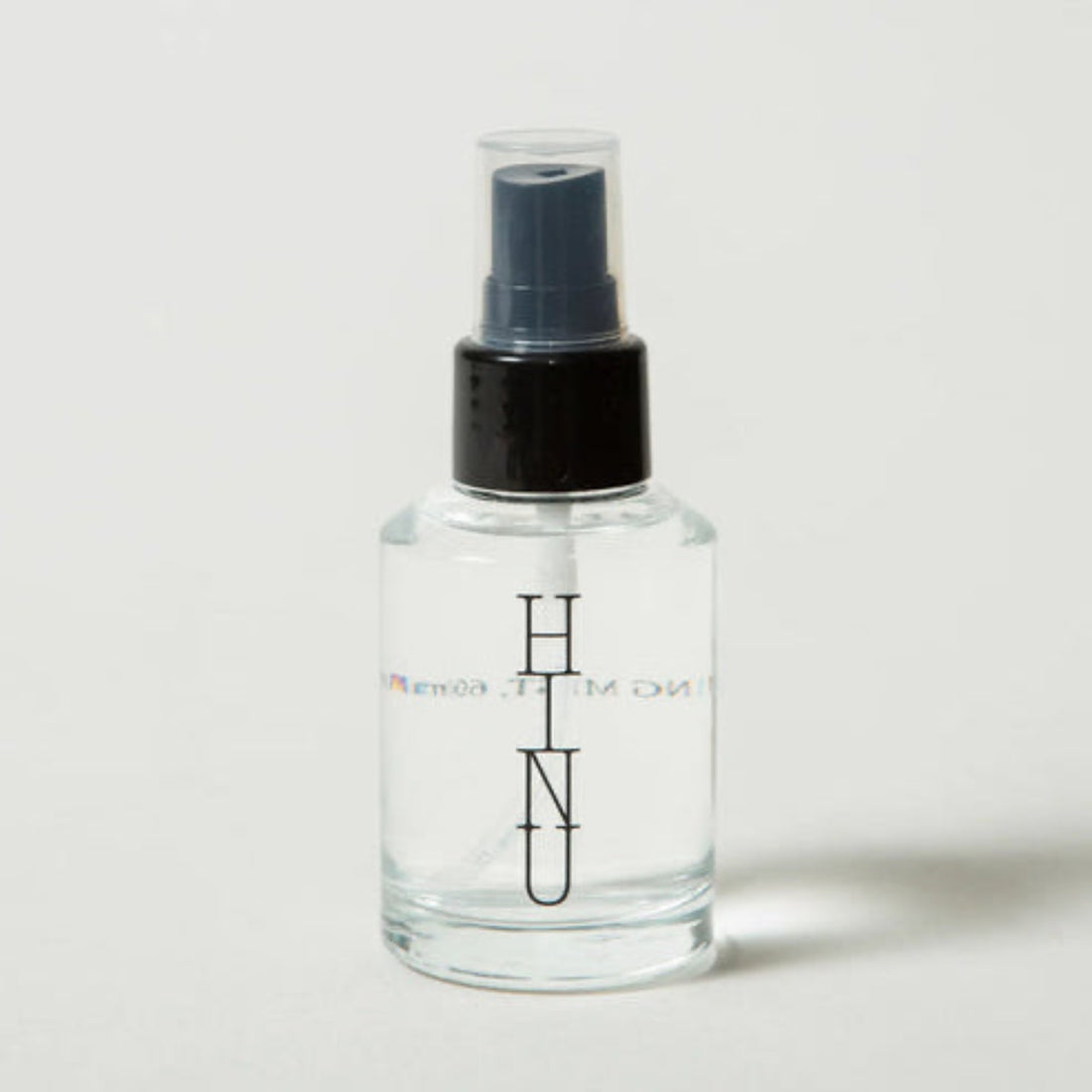 Clear spray bottle with black nozzle on a light gray background