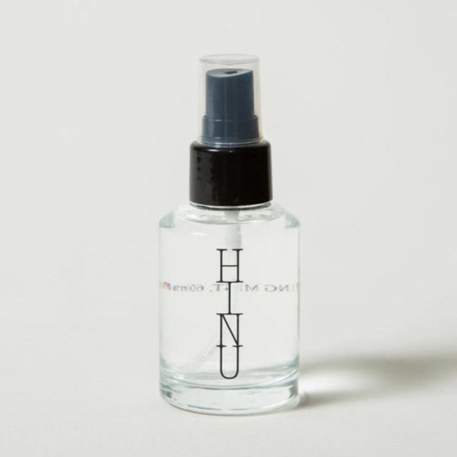Clear spray bottle with black nozzle on a light gray background