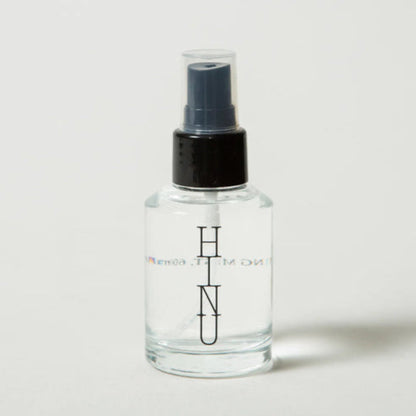 Clear spray bottle with black nozzle on a light gray background