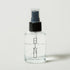 Clear spray bottle with black nozzle on a light gray background