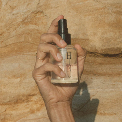 Hand holding a perfume bottle labeled &