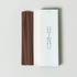 Brown incense sticks next to a white box with &