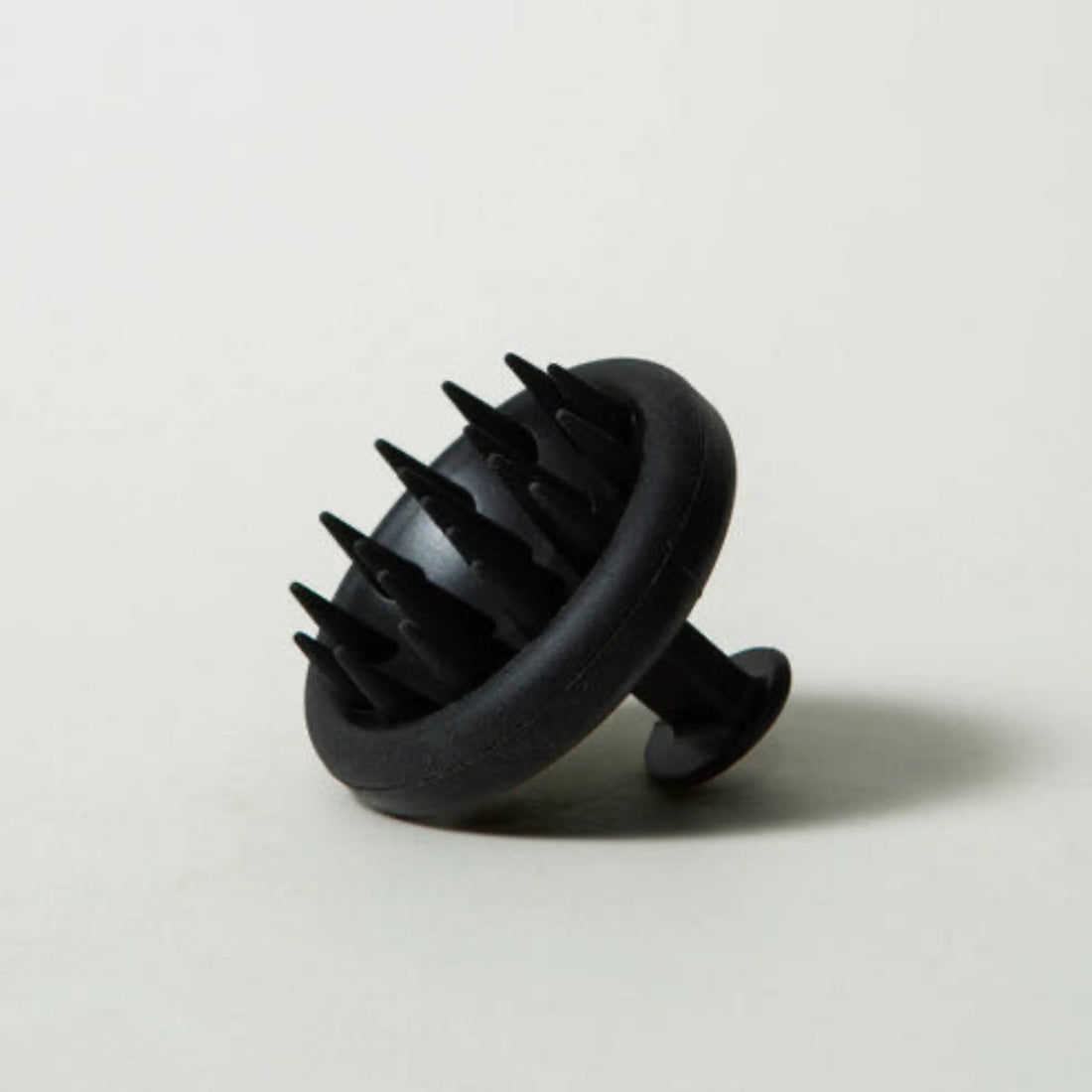 Black scalp massager on a light gray background
