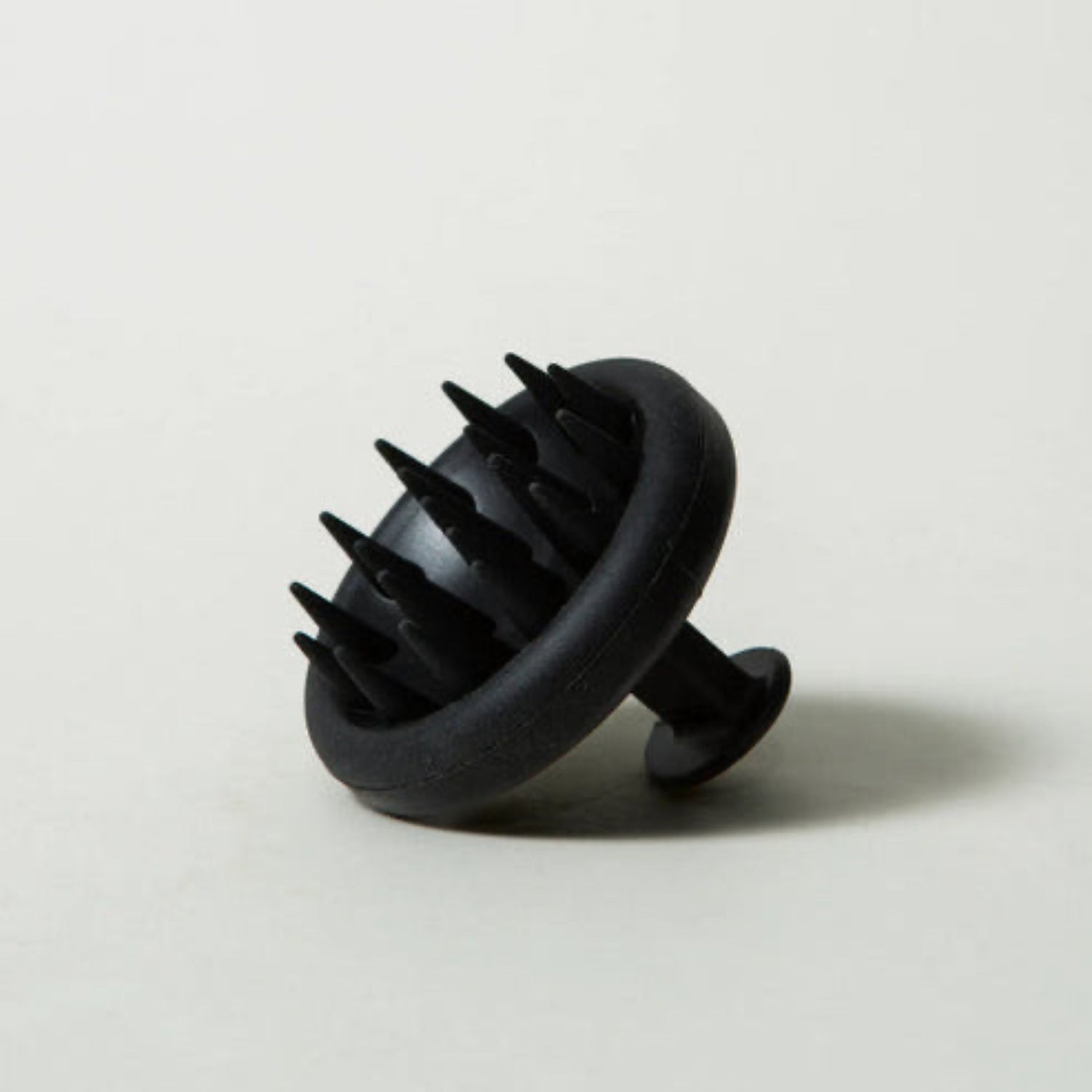 Black scalp massager on a light gray background