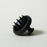 Black scalp massager on a light gray background