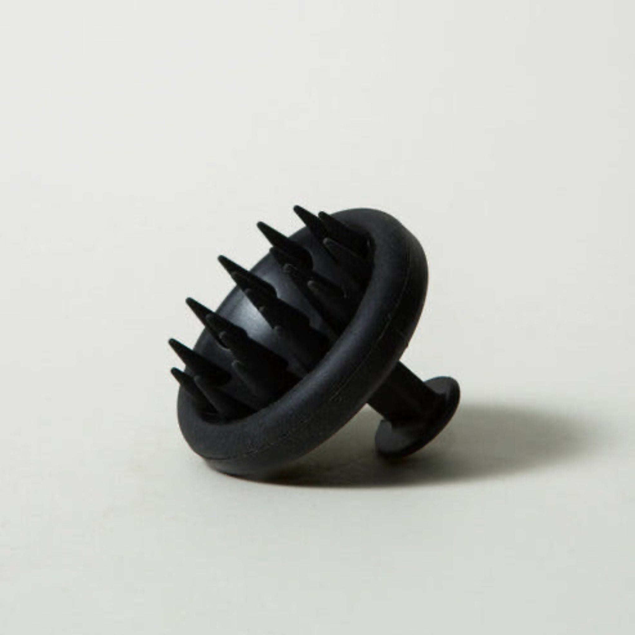 Black scalp massager on a light gray background