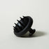 Black scalp massager on a light gray background