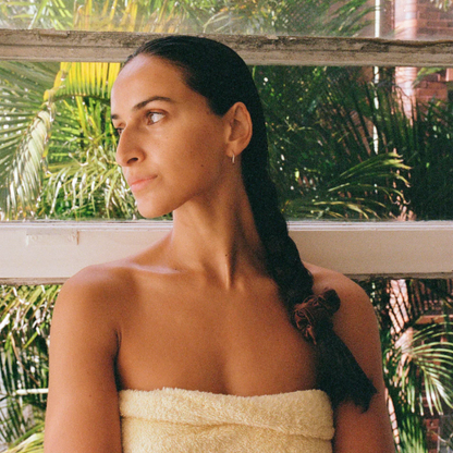 Woman with a braided hairstyle standing in front of green foliage