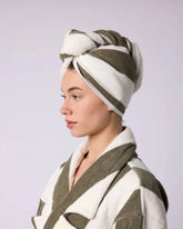 Woman wearing a green and white striped towel hair wrap on her head with a matching robe.