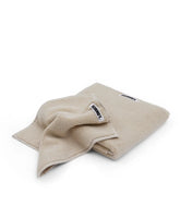 Folded beige towel with a brand logo on a white background