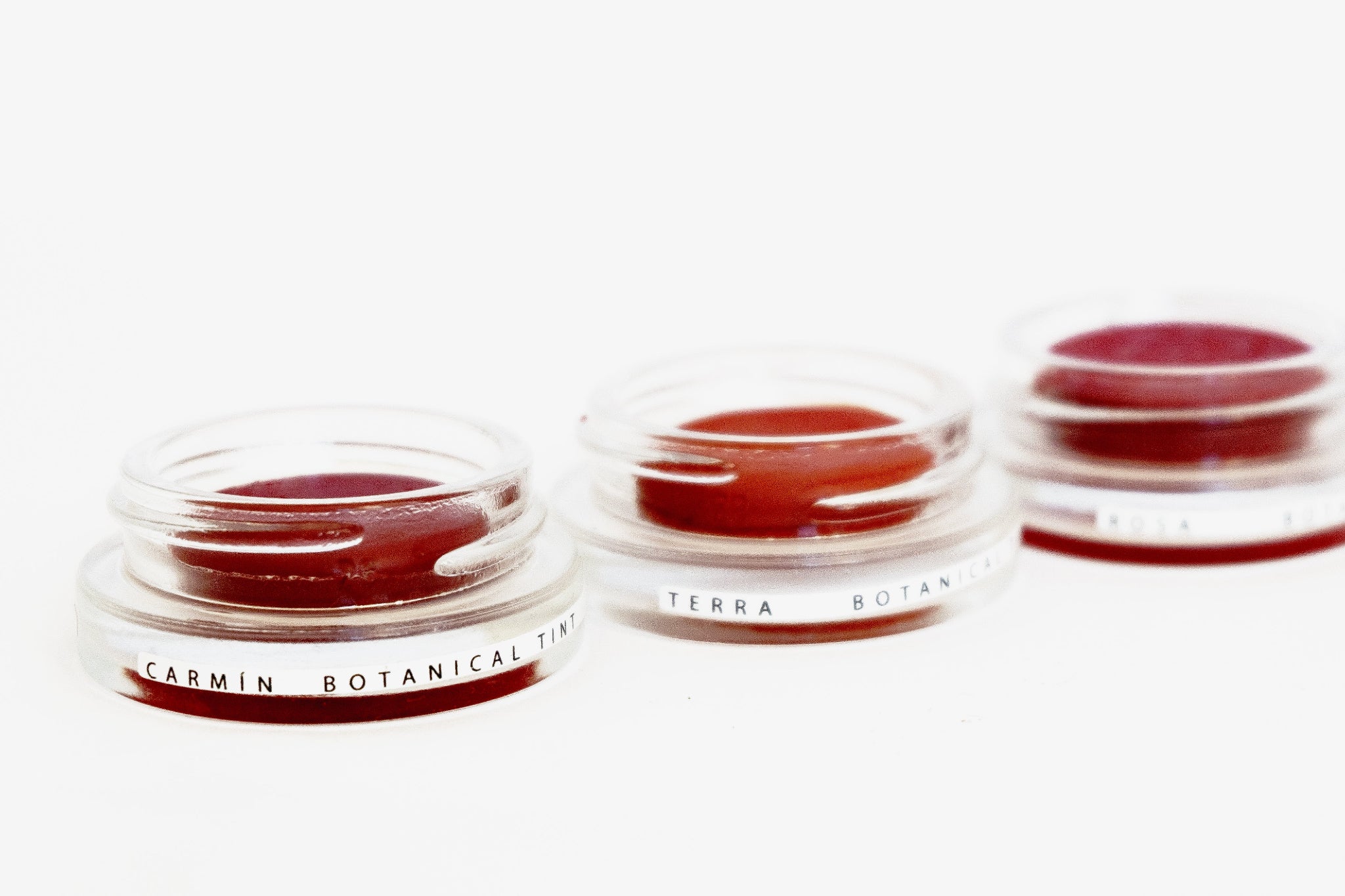 Three glass pottles in a row containing three shades of natural pigment lip tints. 