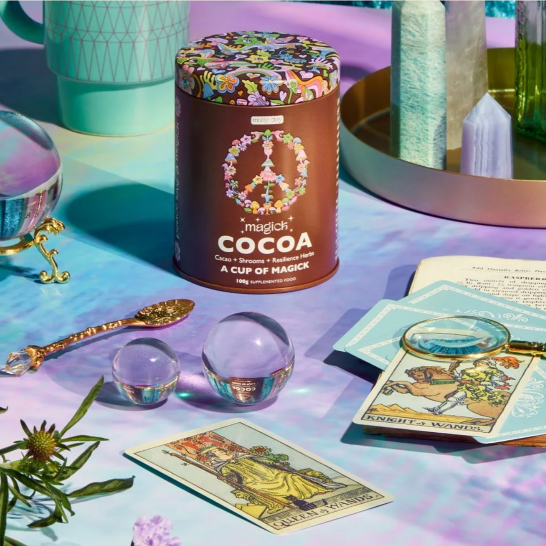 Magick Cocoa displayed with crystals, herbs, and tarot cards. 