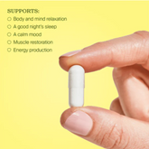 Hand holding a white capsule with text on a yellow background