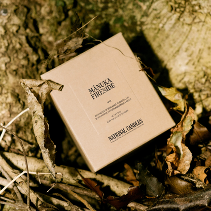 Box of Manuka Fireside candles by National Candles on a natural background with leaves and wood.