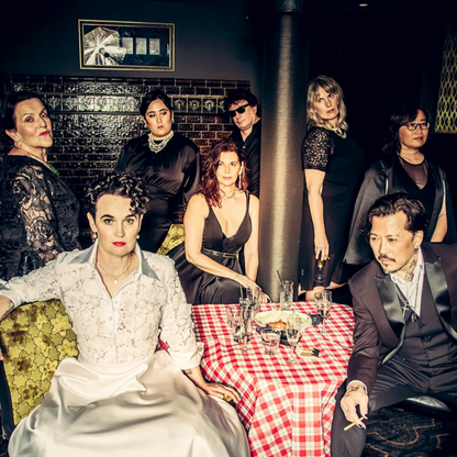 Group of people in formal attire around a table with a checkered tablecloth in a dimly lit room.