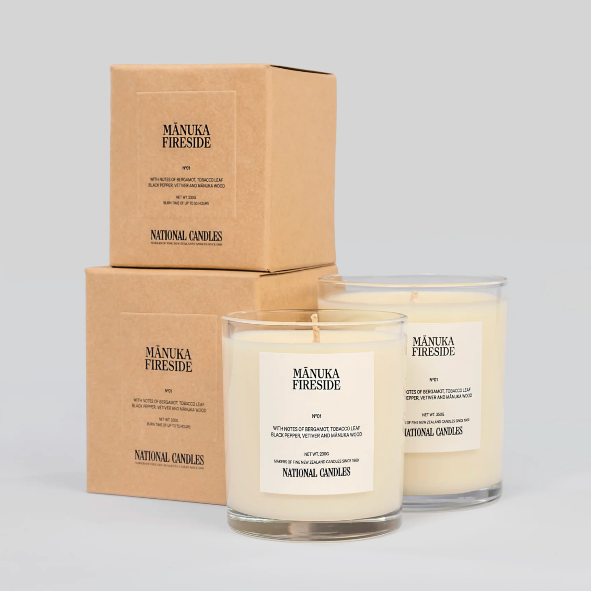 Two Manuka Fireside candles with their packaging on a light gray background