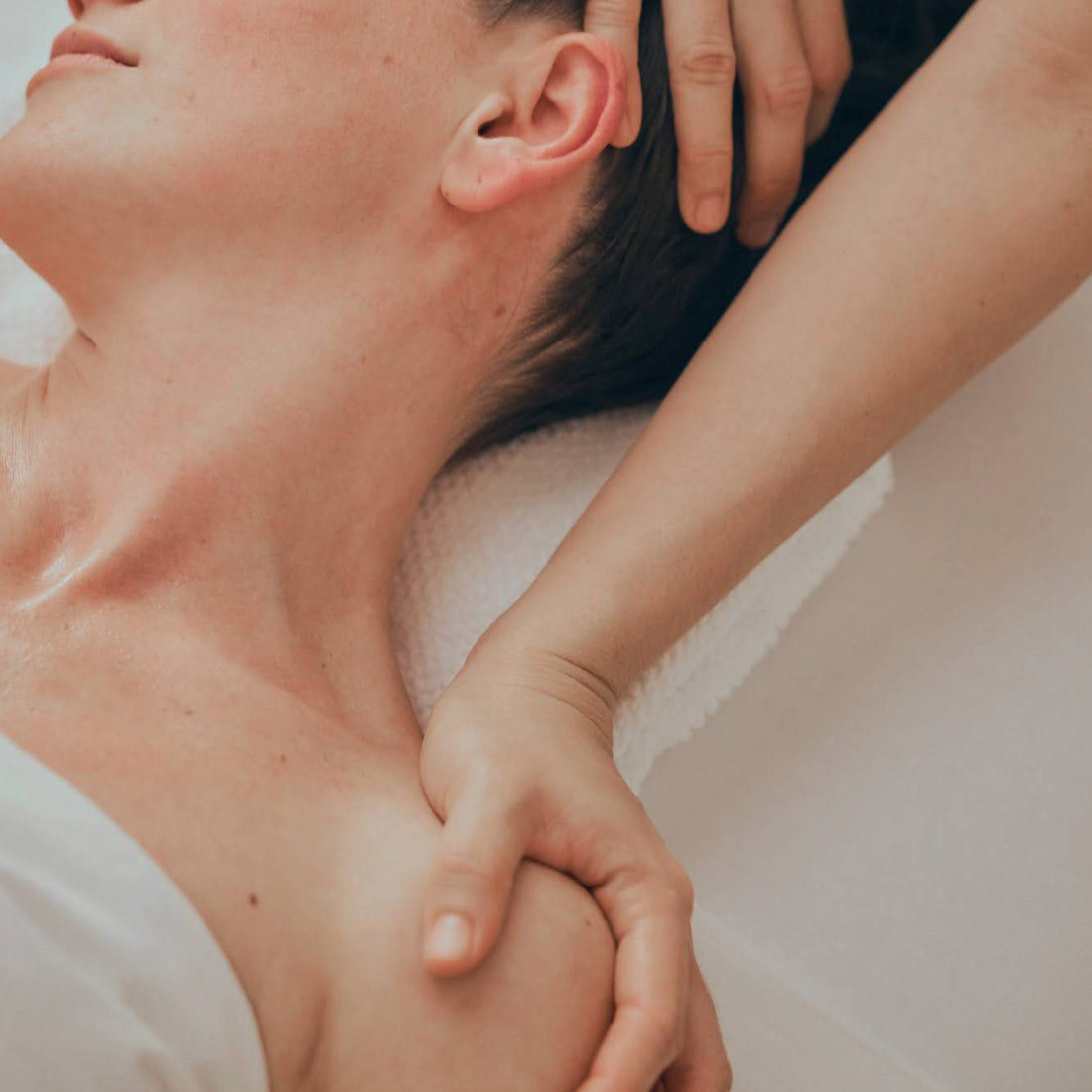 Massage therapist stretching clients neck by pressing one hand on the head and the other on the shoulder in the opposite direction. 