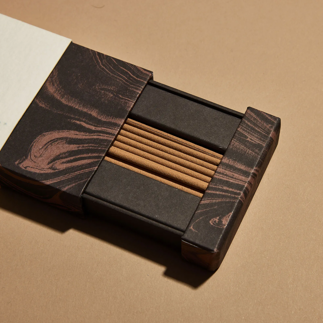 Open box of brown sandalwood incense sticks.