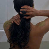 Person with wet hair using scalp massager in the bath.