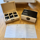 Wooden box with small bottles of essential oils, a menu, and a card on a wooden surface.