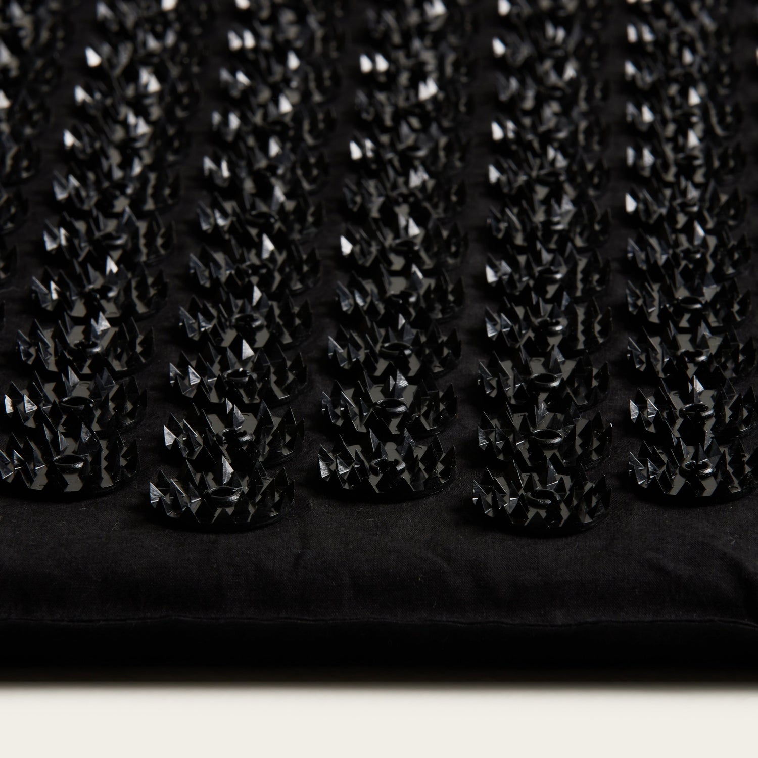 Close-up of a black textured fabric with small diamond patterns.