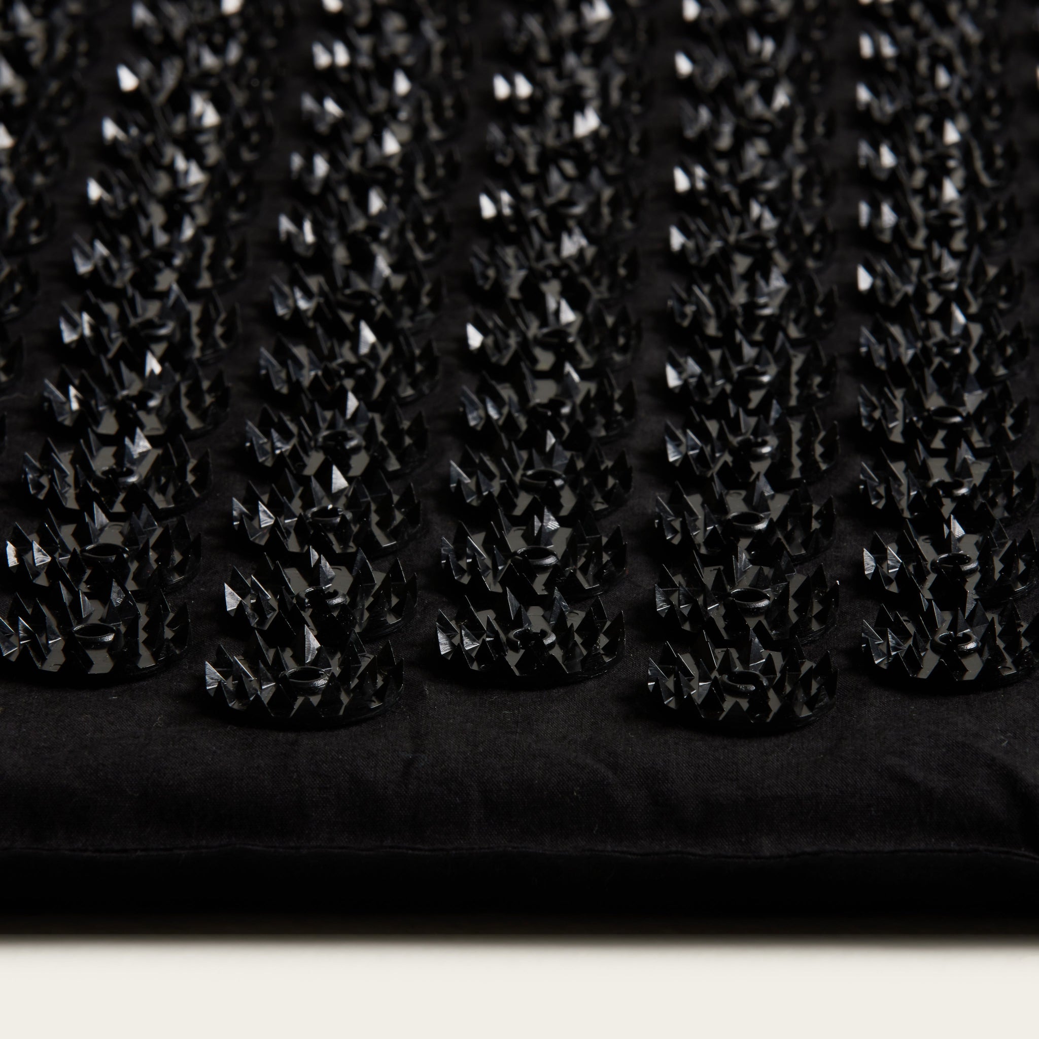 Close-up of a black textured fabric with small diamond patterns.
