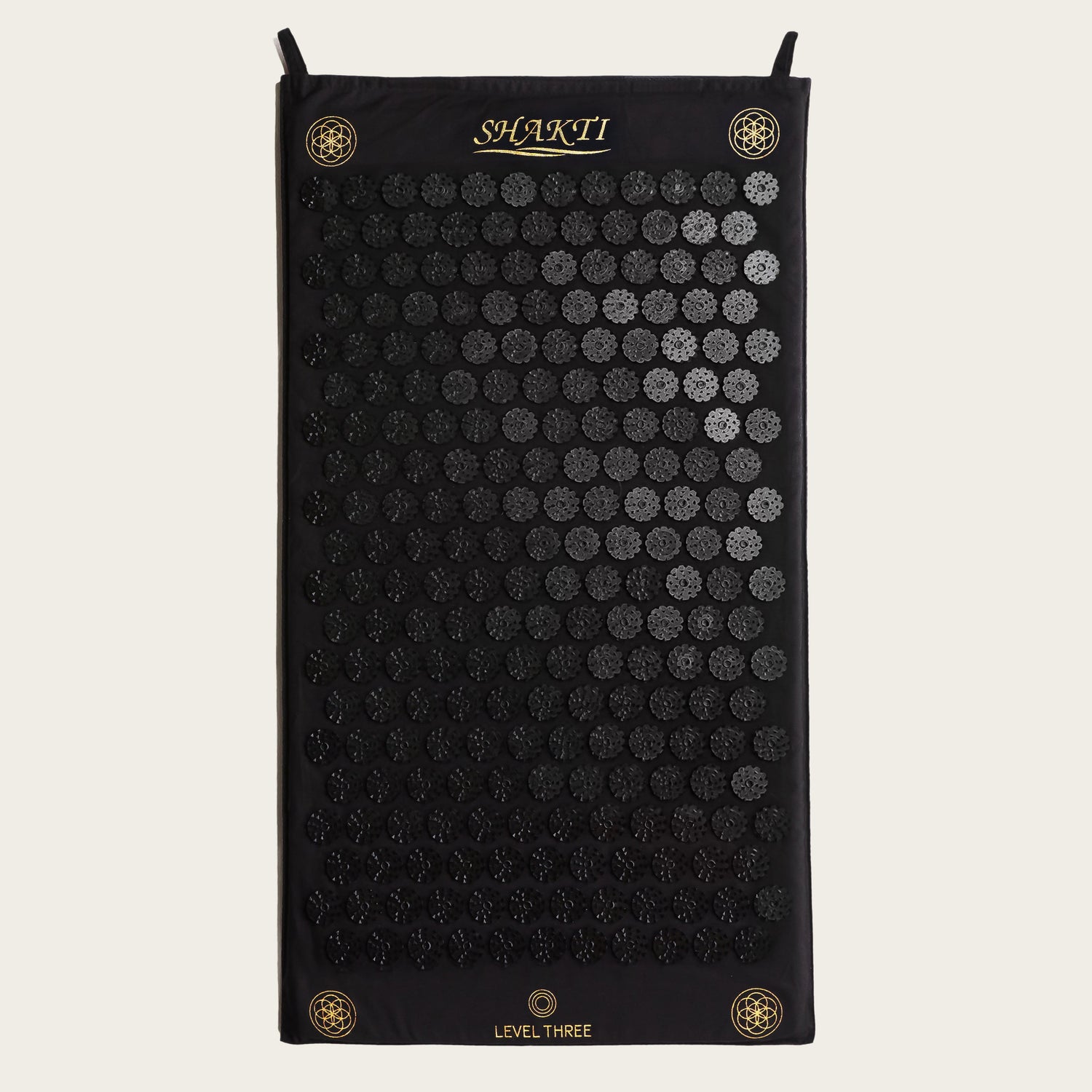 Black acupressure mat with circular patterns on a white background, featuring the brand &