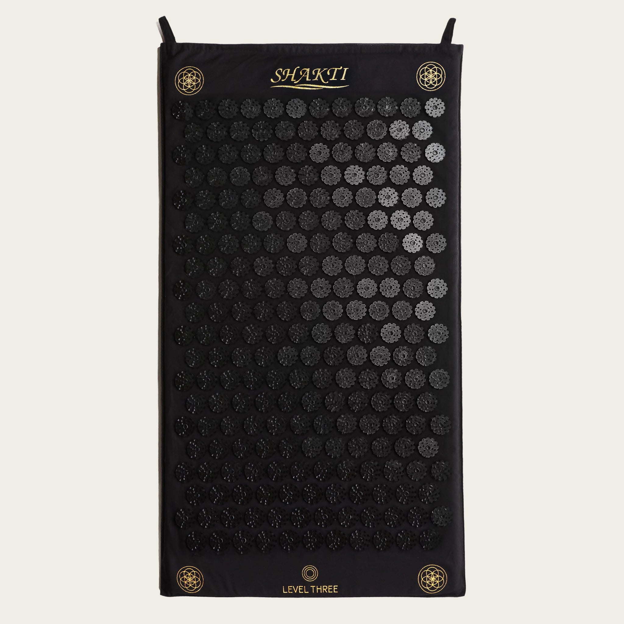 Black acupressure mat with circular patterns on a white background, featuring the brand &