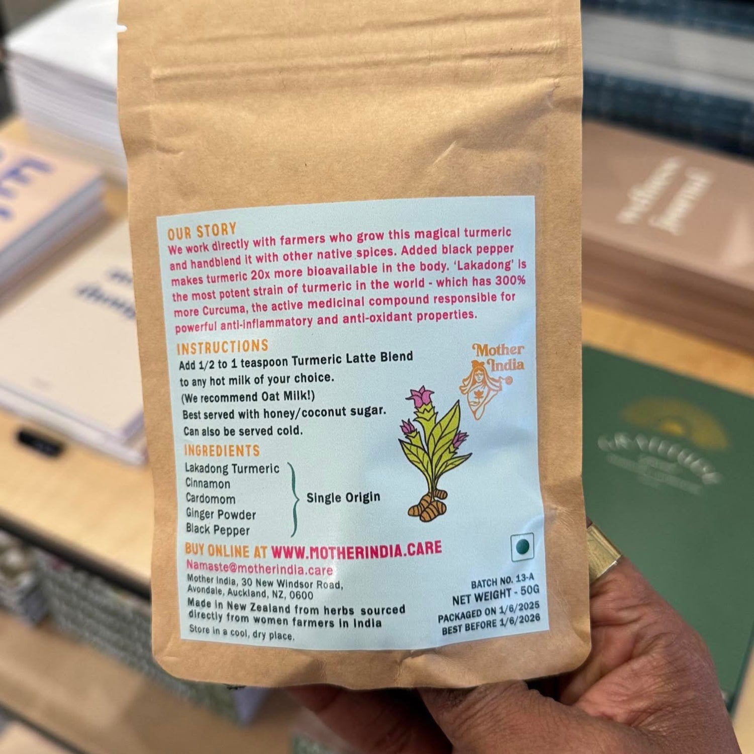 Hand holding a brown package with the Mother India Turmeric Latte product information. 