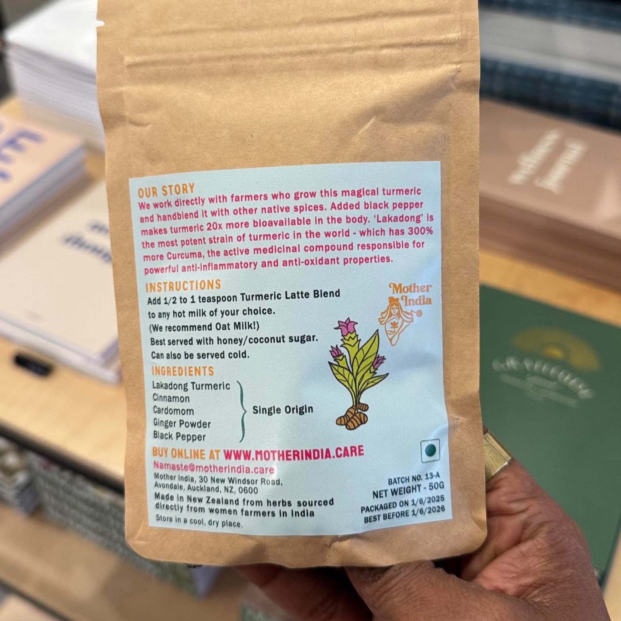Hand holding a brown package with the Mother India Turmeric Latte product information. 