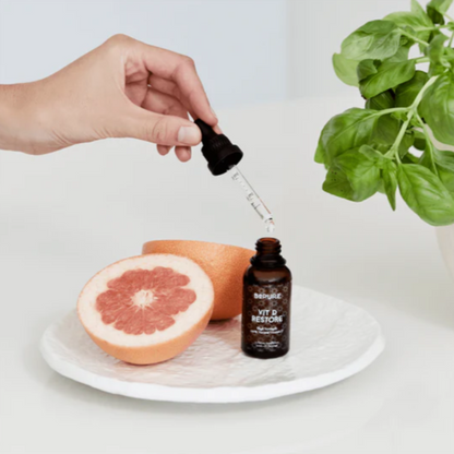 Hand using a dropper to vitamin D liquid from a bottle labeled &