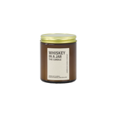 Amber glass jar with brass lid containing whiskey in a jar candle on white background. 
