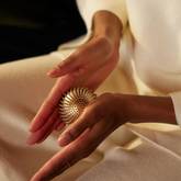 Close-up of hands holding a textured gold ball against a neutral background