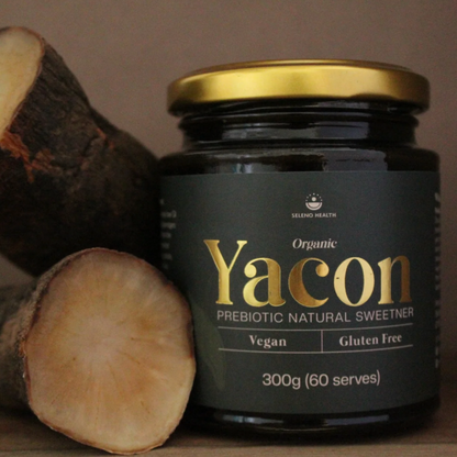 Jar of Organic Yacon prebiotic natural sweetener with yacon roots on a wooden surface.